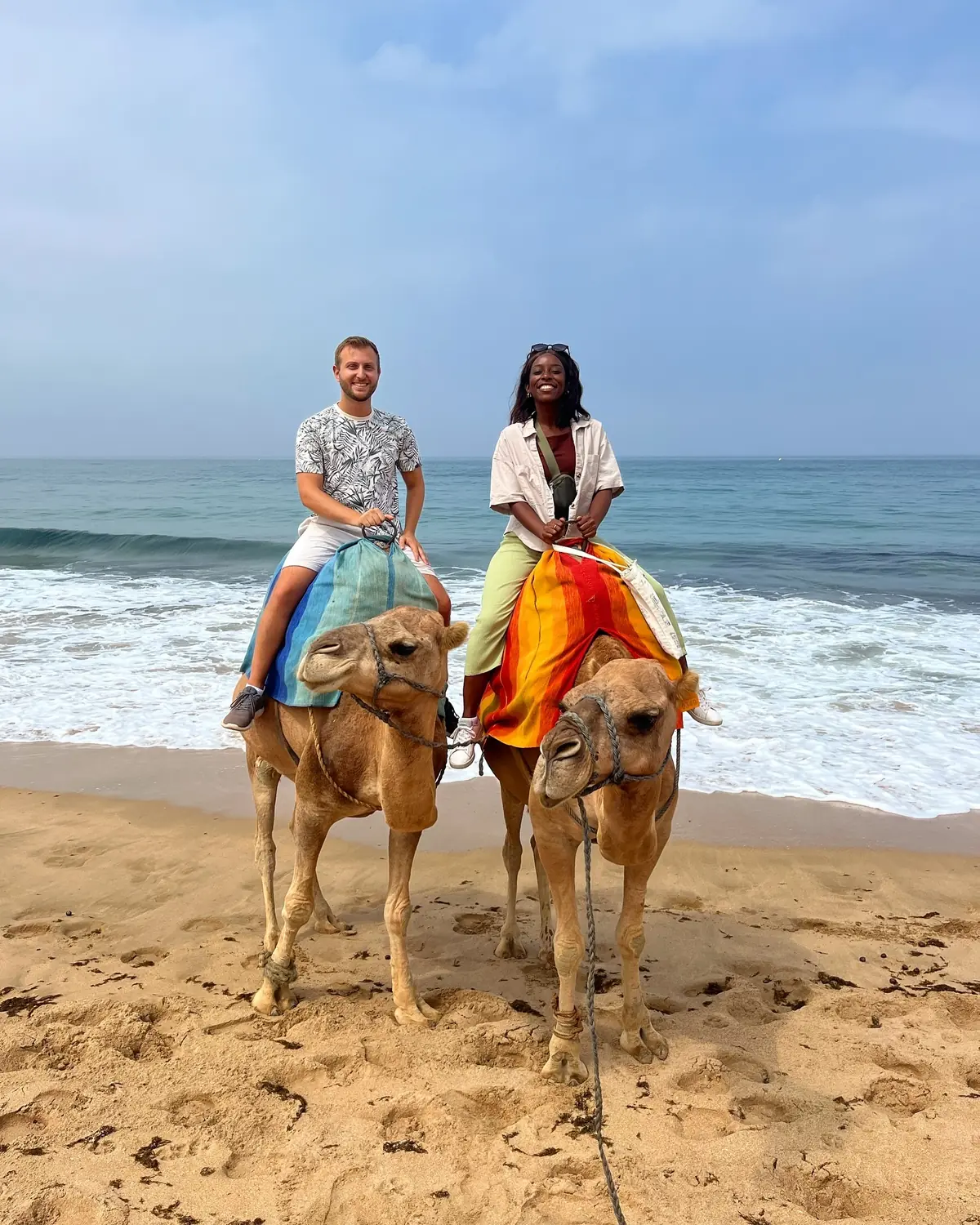 Us riding two camels along the Tangier beach with the waves behind
