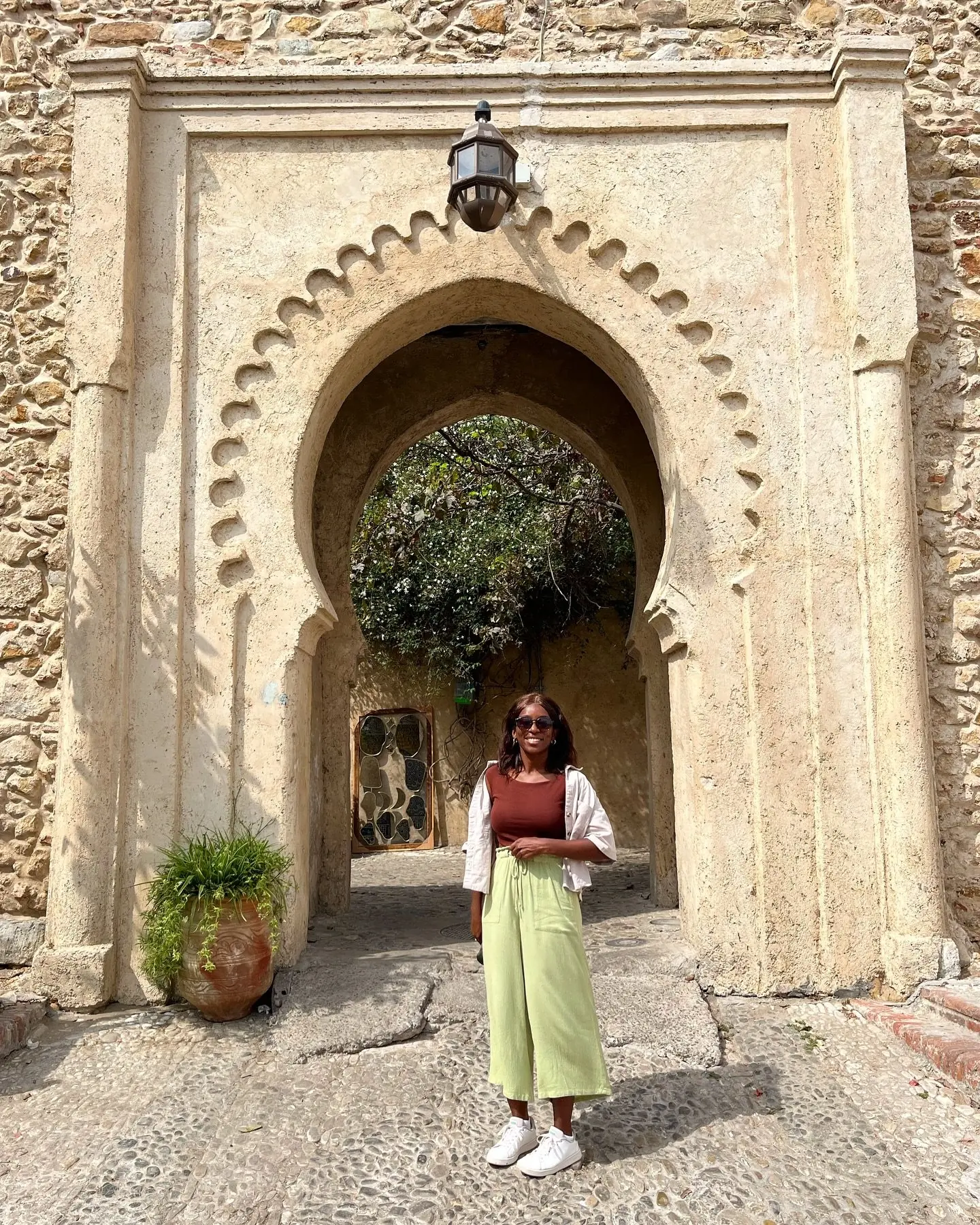 Melody under a scalloped stone kasbah gateway with a hanging lantern in Tangier