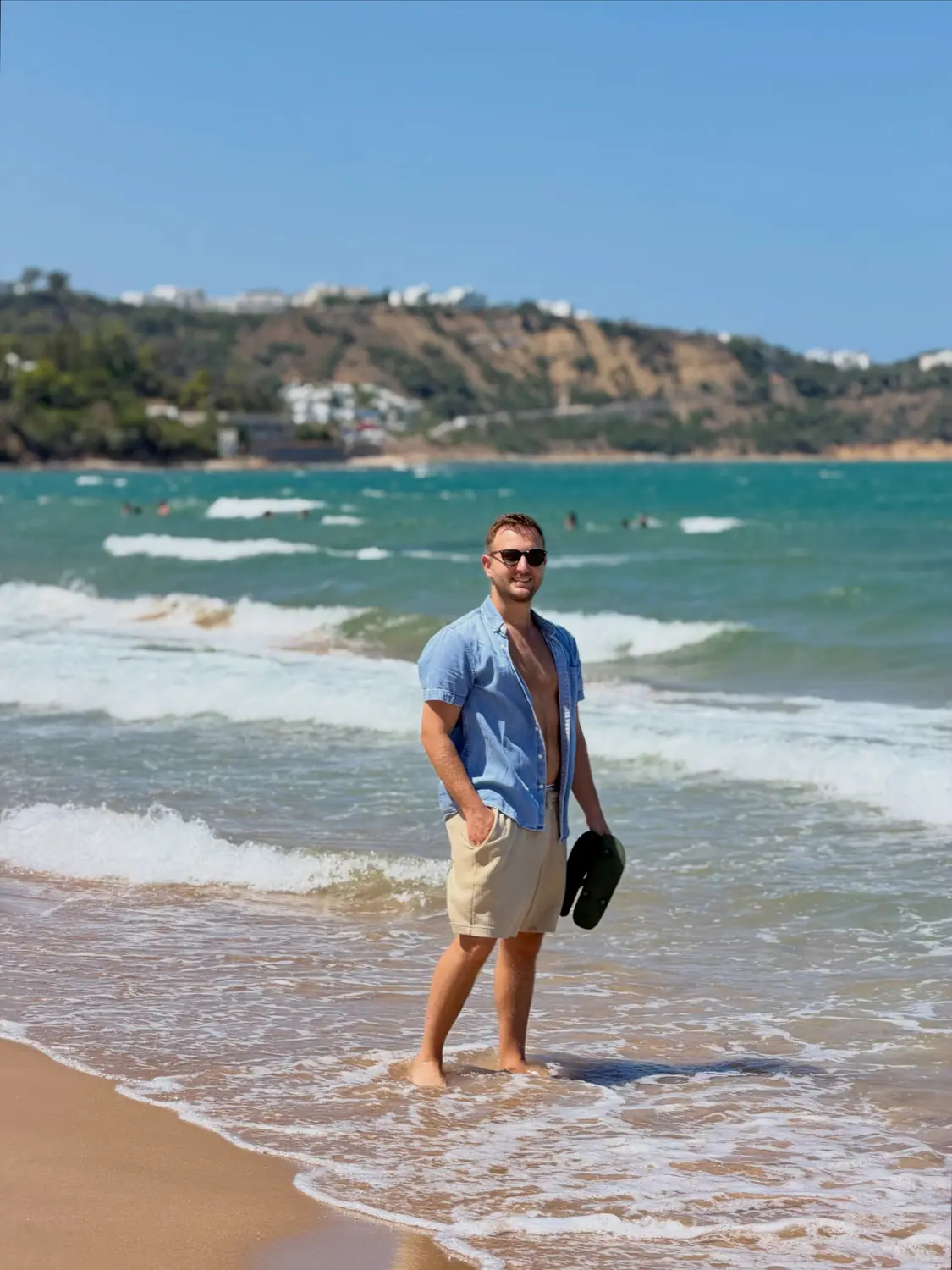 Andrew paddling at the shoreline of a Tunis beach with turquoise water