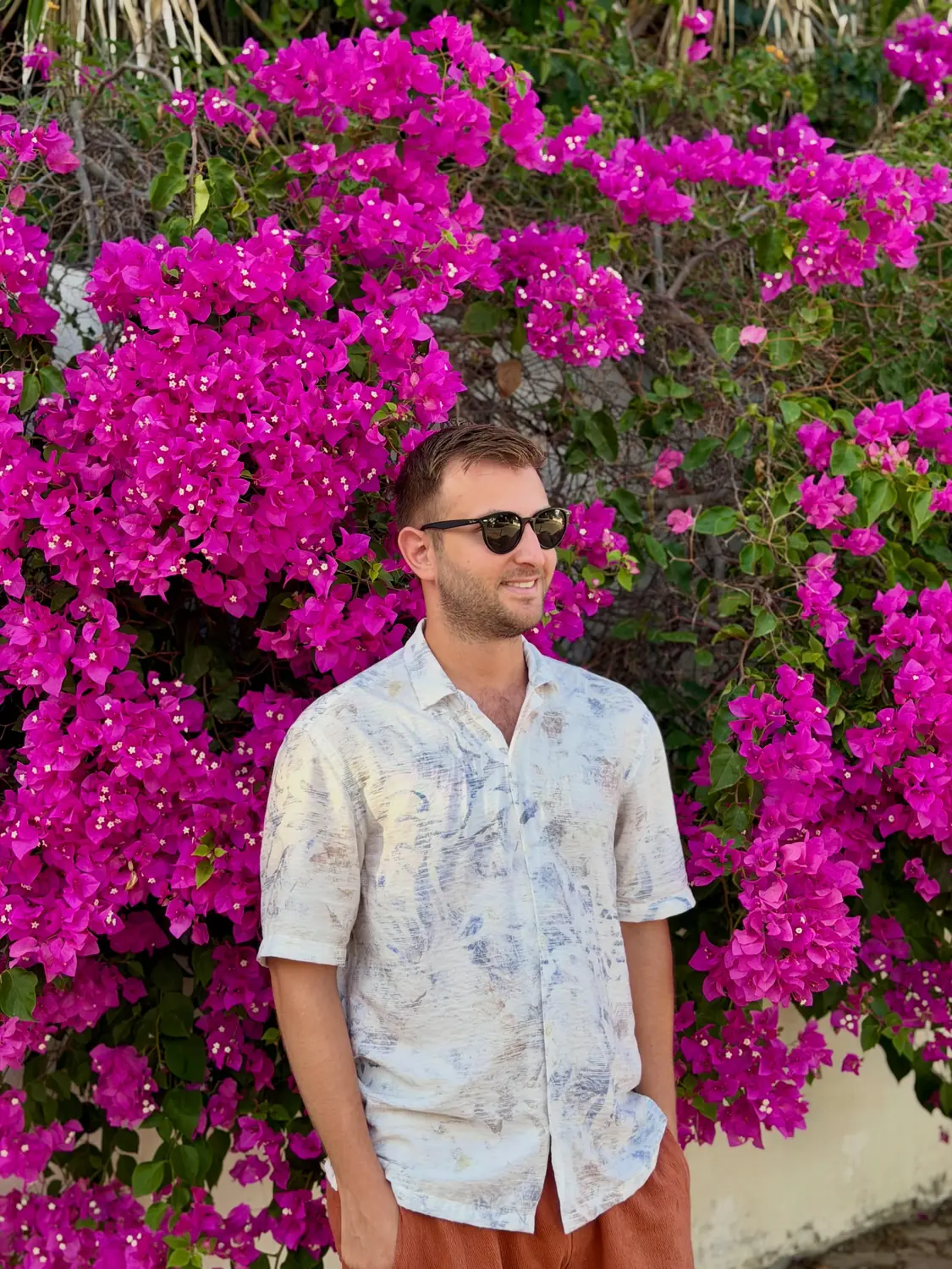 Andrew in front of a wall of magenta bougainvillea