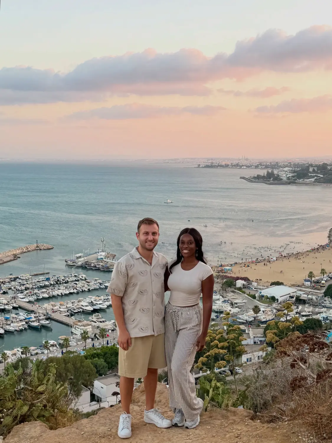 Us at a clifftop viewpoint above the Sidi Bou Said marina at sunset