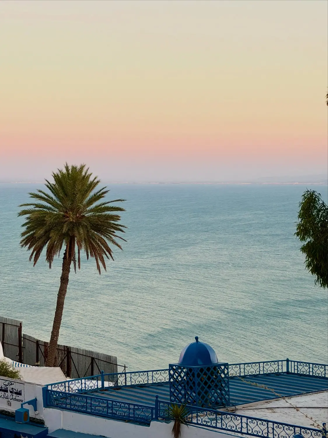 A blue-domed clifftop terrace in Sidi Bou Said above the Mediterranean at sunset