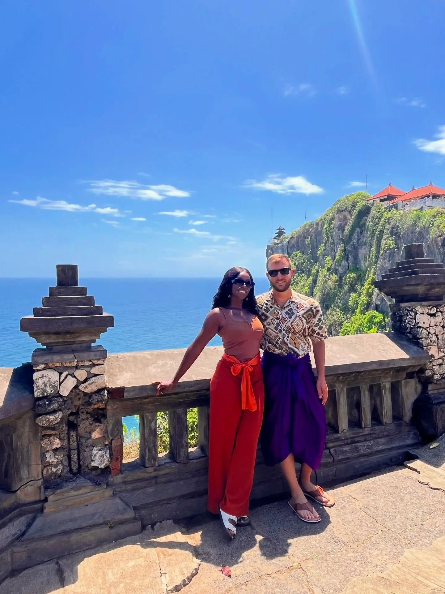 Couple at the clifftop railing of Uluwatu Temple above the ocean