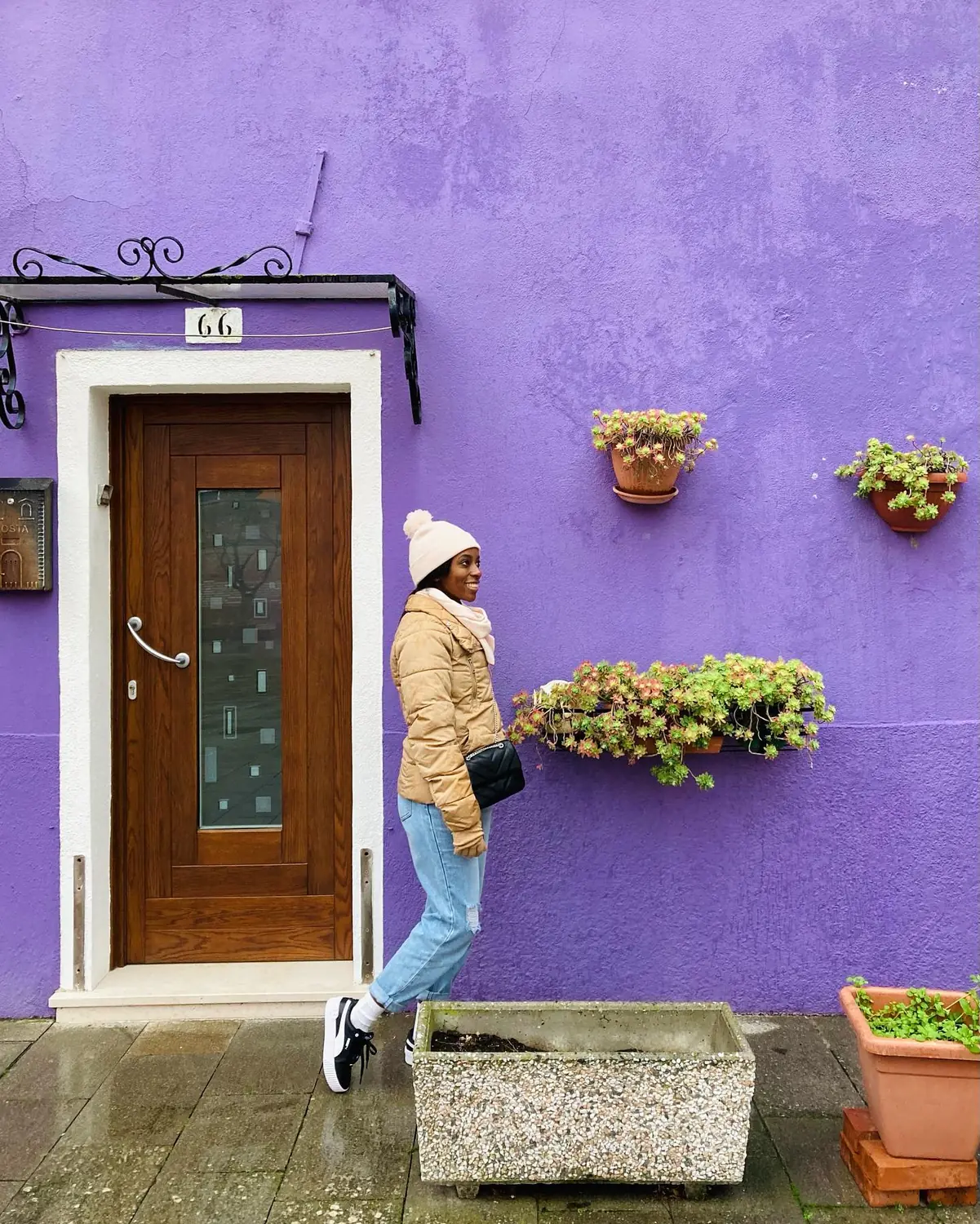 Melody beside a bright purple house with flower boxes on Burano