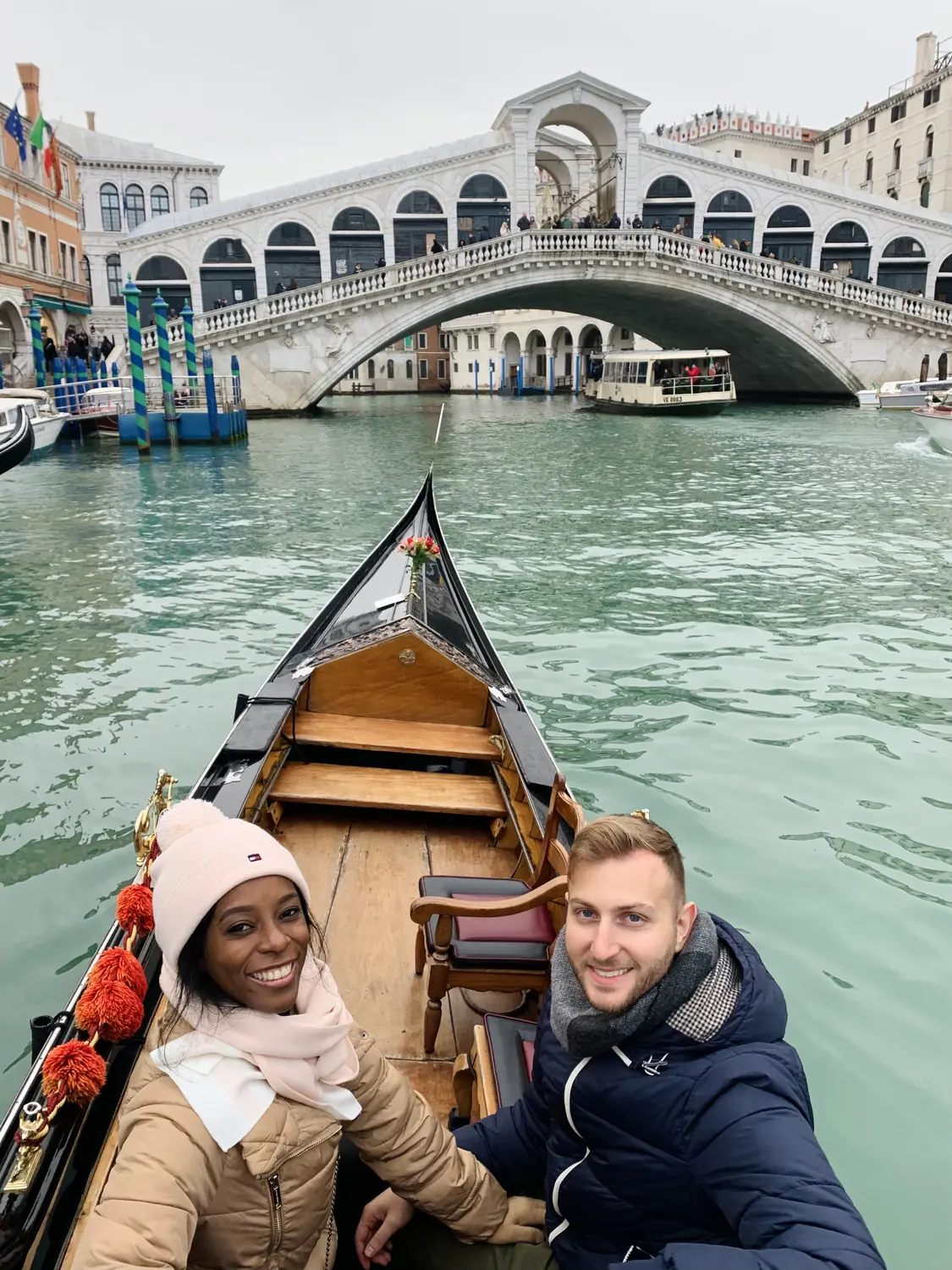 Selfie of us on a gondola ride with the Rialto Bridge behind in Venice