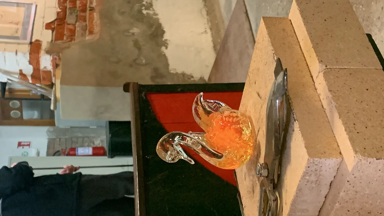 A glowing orange glass swan being shaped at a Murano glassmaking workshop